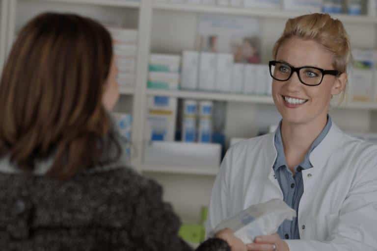 Pharmacienne souriante qui donne des médicaments à une cliente