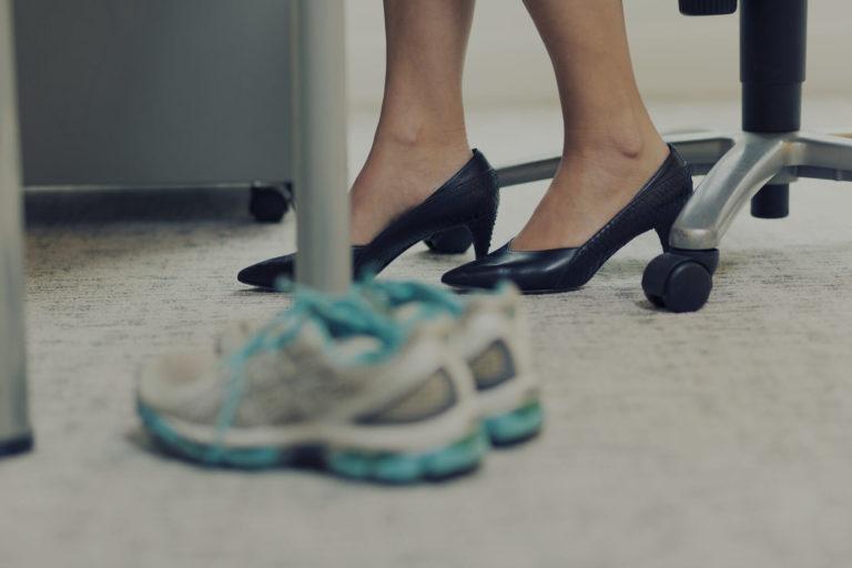 Paire de chaussures de sport à côté d'une femme portant des talons