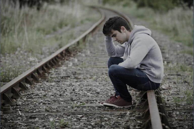 Jeune homme en dépression au milieu d'un chemin de fer