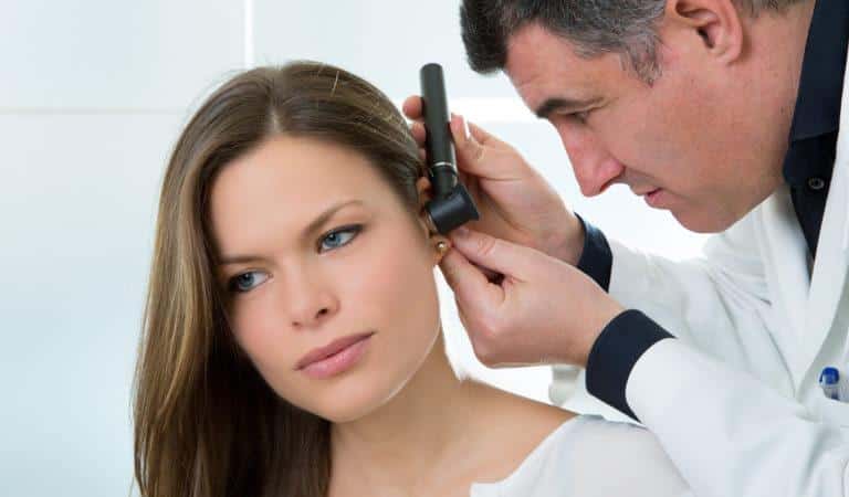 médecin homme qui regarde les oreilles d'une femme à l'aide d'un otoscope